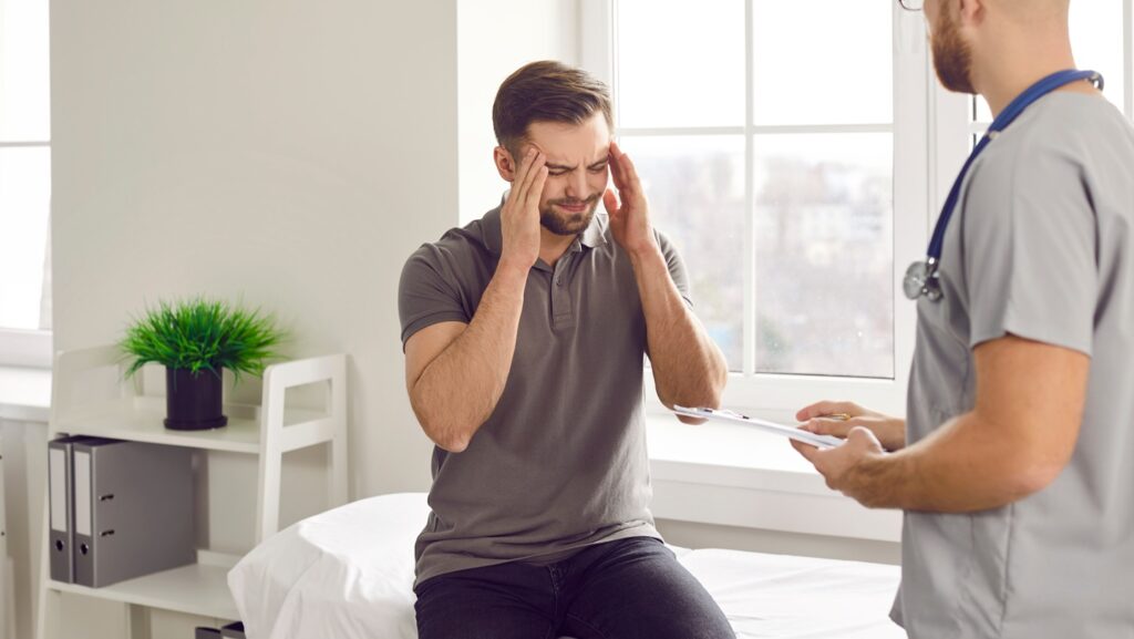 Male,Patient,With,Terrible,Headache,Visiting,His,Doctor.,Young,Man